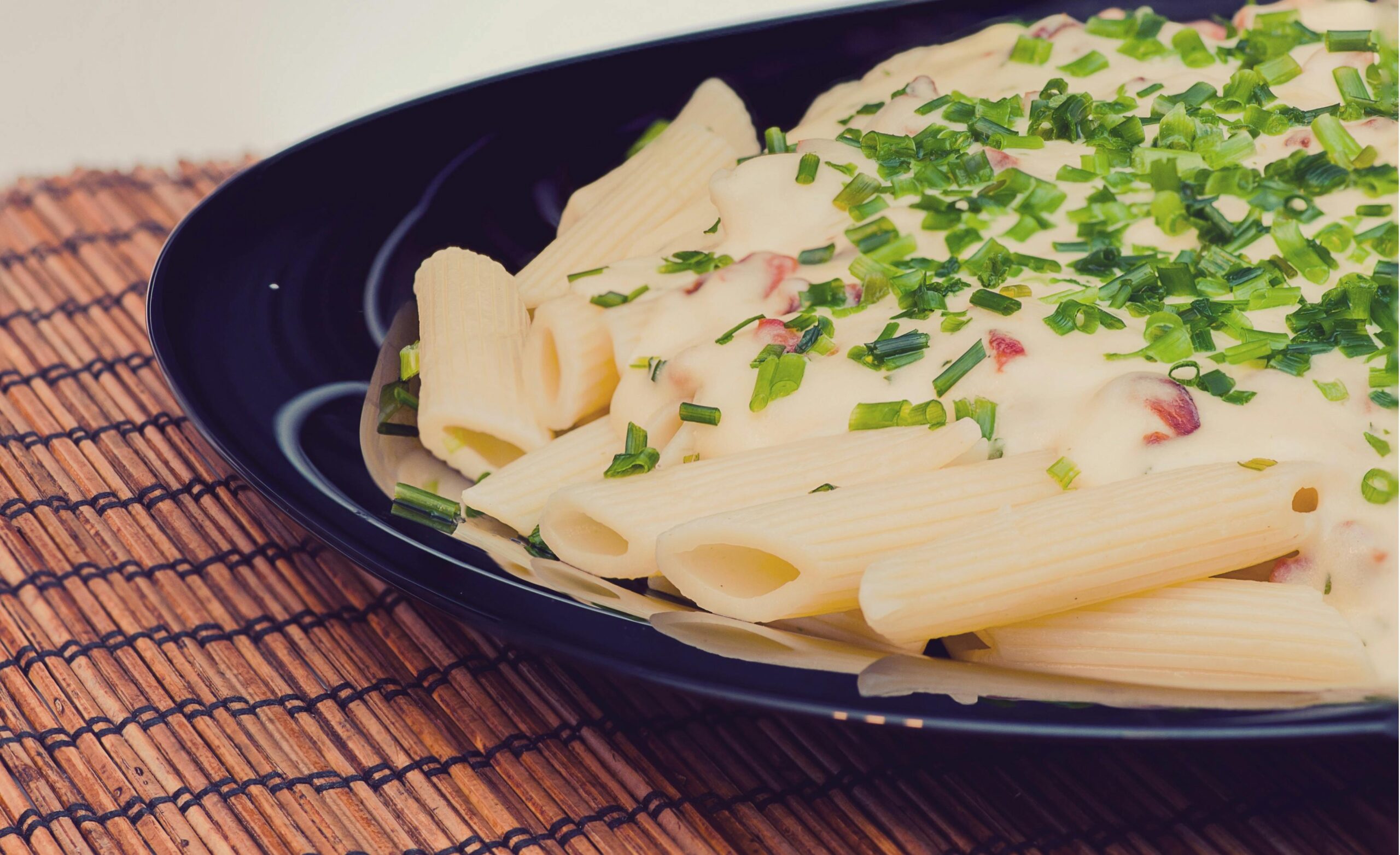 Delicious penne pasta with creamy cheese sauce topped with fresh herbs.