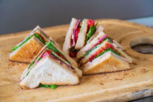 Tasty club sandwich with fresh ingredients on a wooden board, perfect for a quick meal.