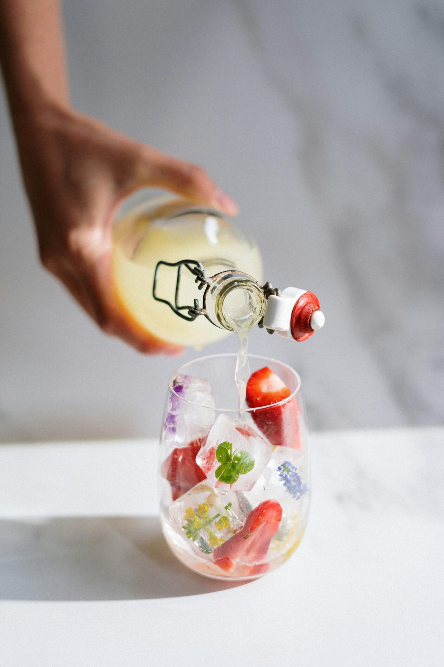 Delicious drink with colorful fruit-infused ice cubes being poured on a bright summer day.