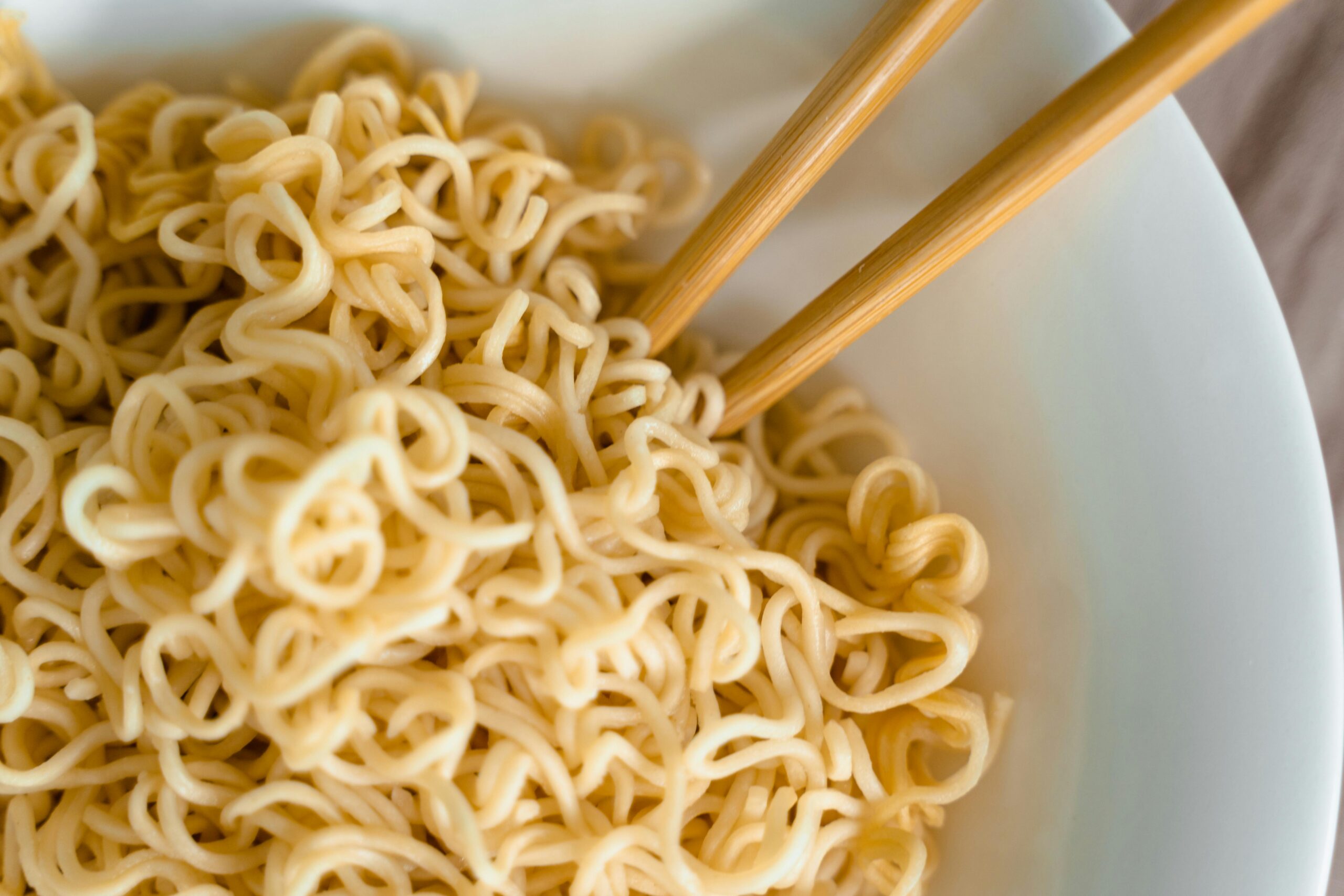 Tasty close-up of cooked noodles in a bowl with chopsticks for an Asian dining experience.